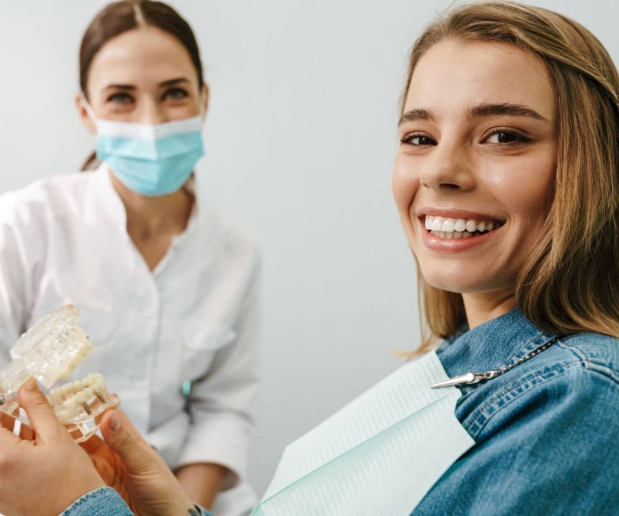 European mid happy dentist woman showing teeth imitation to her patient in dental clinic